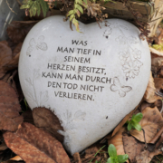 Stein in Herzform mit einfühlsamen Text auf Herbstlaub